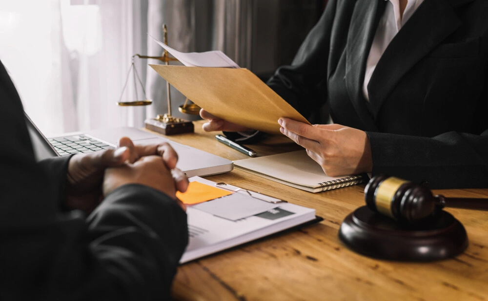 Business and lawyers discussing contract papers with brass scale on desk in office.