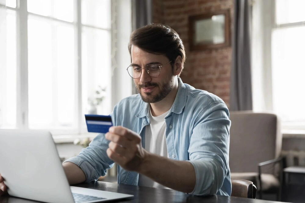 Satisfied shopper man using credit card with good term conditions